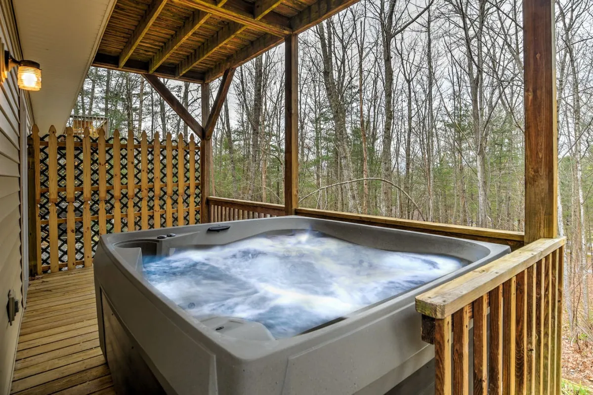 A soothing hot tub situated on a wooden deck, framed by mature trees that create a cocoon of privacy. The scene captures the essence of relaxation, inviting you to unwind while soaking in the sights and sounds of the Carolina outdoors. The natural setting enhances the sense of escape and leisure described in the section.