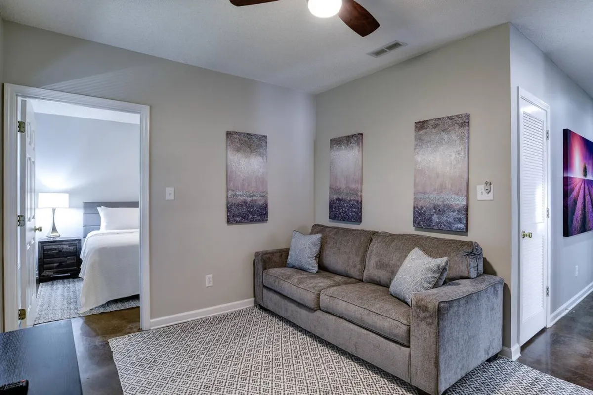 A cozy living area featuring a comfortable sofa, modern artwork, and a stylish light fixture. The inviting arrangement suggests an ideal spot for socializing, relaxing after a night out, or enjoying quality time with friends and loved ones.