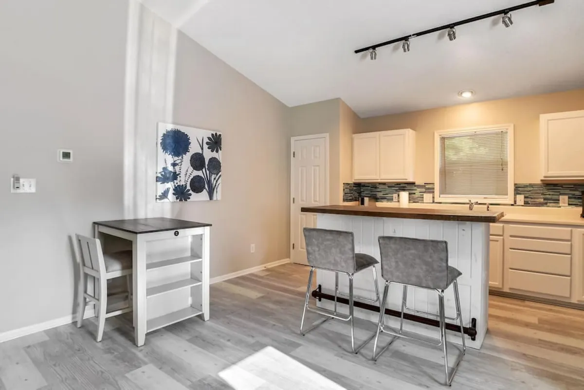 A spacious kitchen centered around a large island with bar stools, complemented by modern wall art. The open-plan layout facilitates easy interaction between people cooking and those seated, inviting both socializing and shared meal preparation.